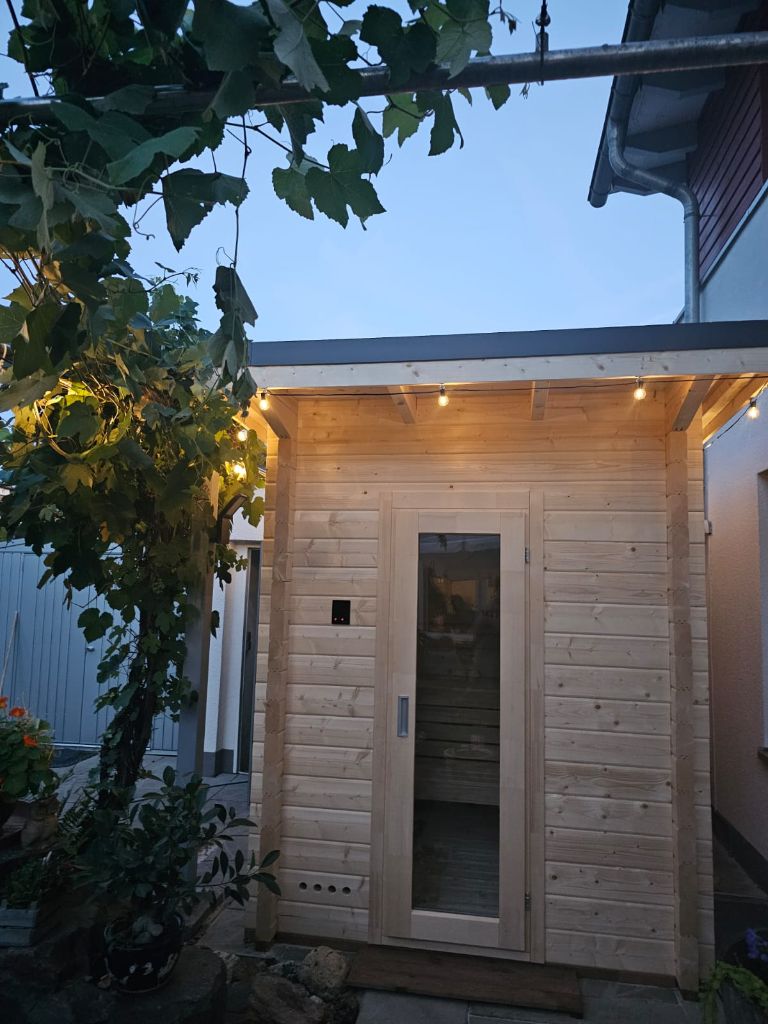 Freistehende Outdoor-Sauna aus Holz im Garten, Abendstimmung